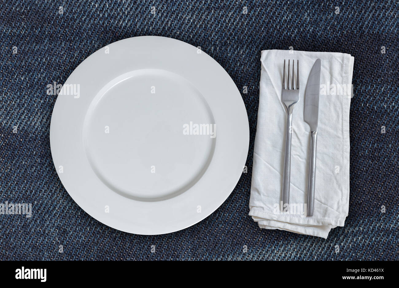 Piastra vuota e posate sul tessuto jeans. Foto Stock