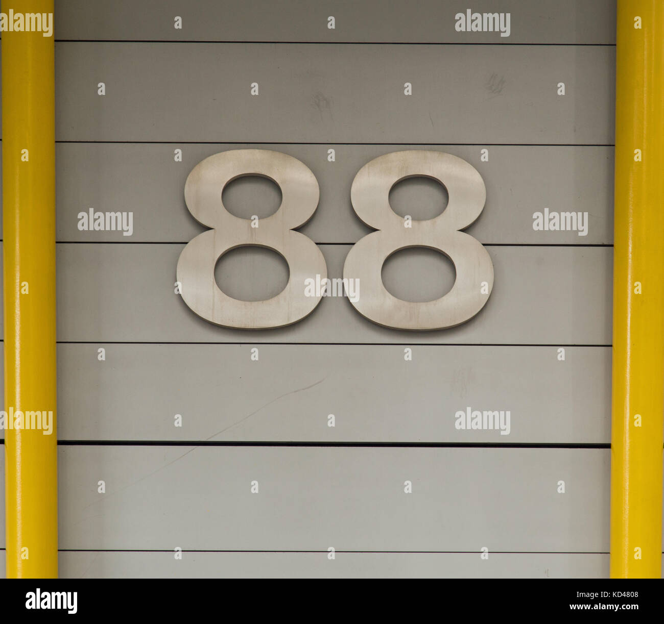 Numeri 88 in argento su sfondo grigio con tubi giallo su entrambi i lati Foto Stock