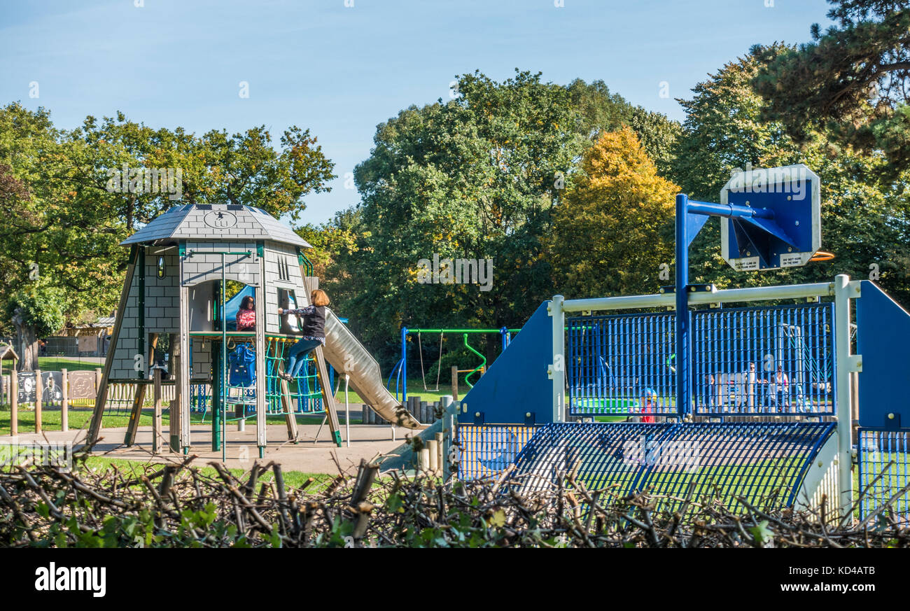 Parco giochi per bambini / area di gioco, con due bambini su un telaio di arrampicata in un giorno caldo e soleggiato inizio autunno. Gunnersbury Park, West London, England, Regno Unito. Foto Stock