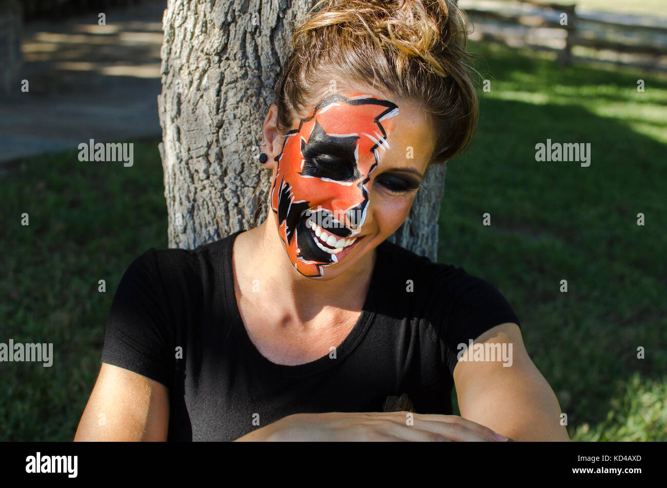 La donna a jack-o-lantern face paint sembra felice e festoso per la caduta di halloween holiday. Foto Stock