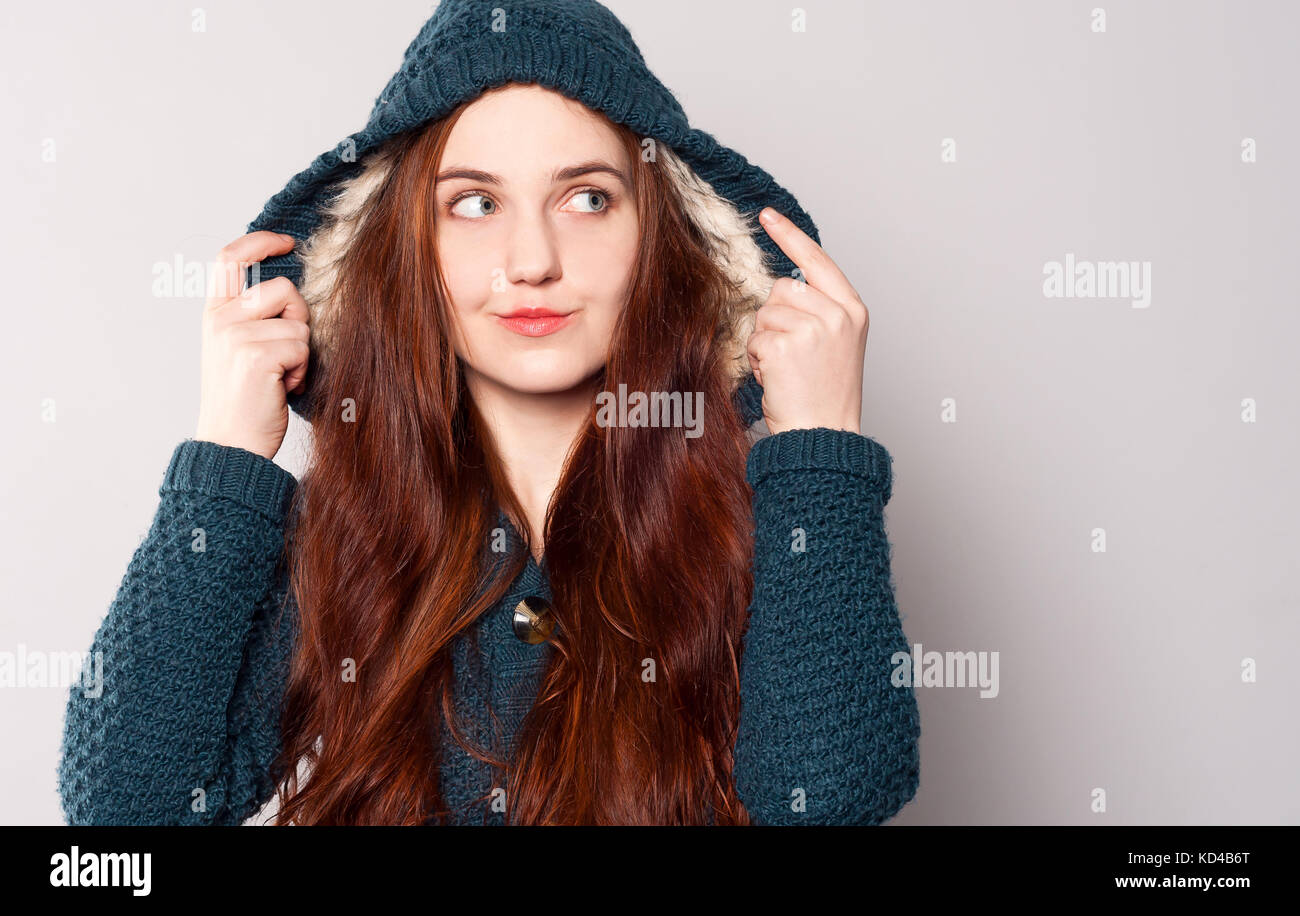 Una bella donna felice con capelli lunghi vestito con una maglia di caldo blu-verde felpa o rivestire con una cappa riscaldata con pelliccia bianca. ragazza guarda. caldo Foto Stock