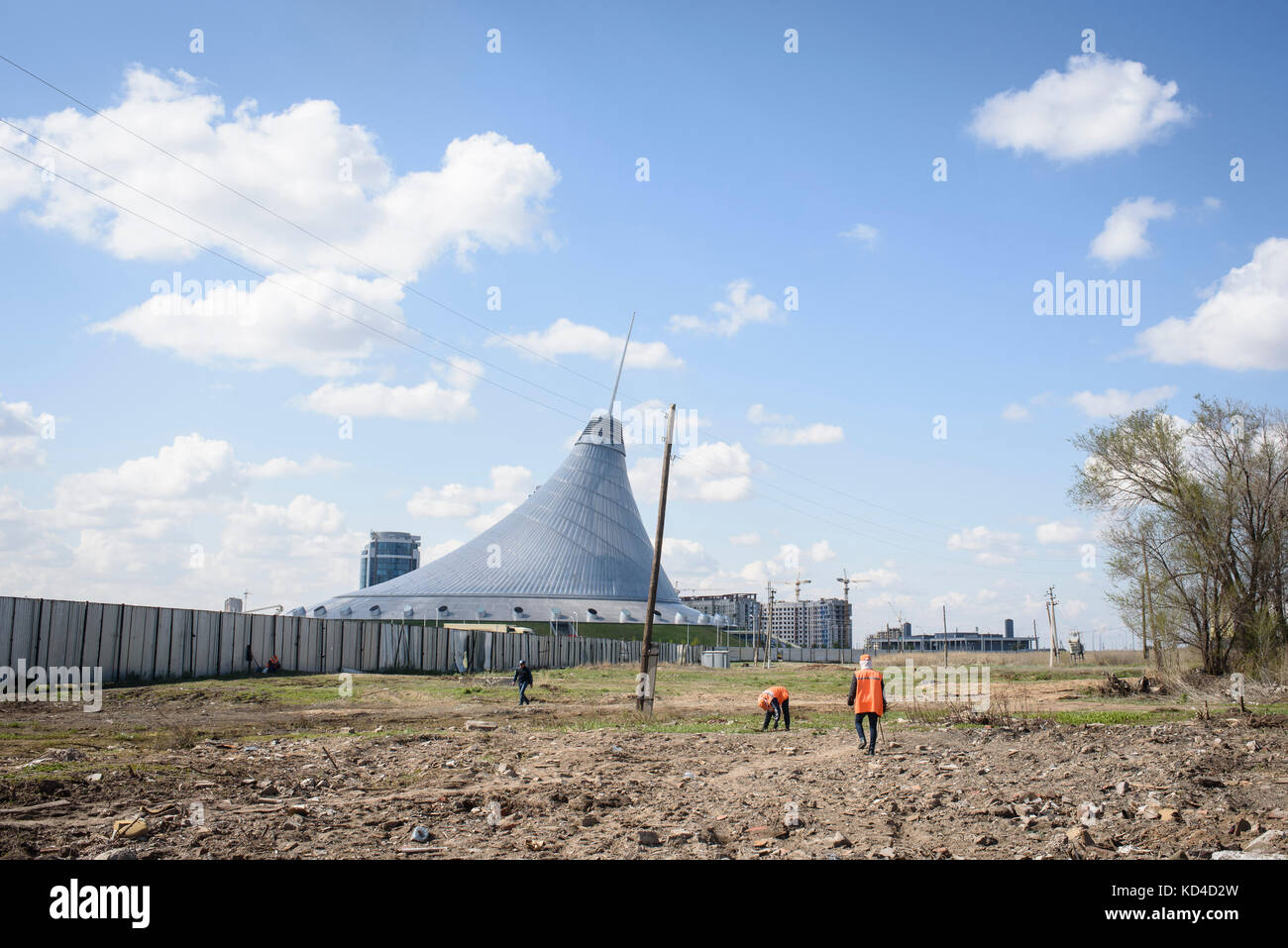 Lavoratori che lavorano in un nuovo cantiere ad Astana. Sullo sfondo, Khan Shatyr, il centro commerciale di yurta di Astana è stato costruito da Norman Foster Foto Stock