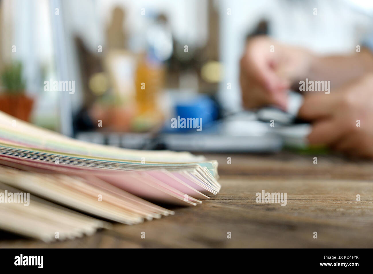 La sfocatura graphic designer che lavorano con il computer e con tonalità di colore della carta per la scelta del colore migliore per il progetto sulla tavola di legno al di fuori della messa a fuoco Foto Stock