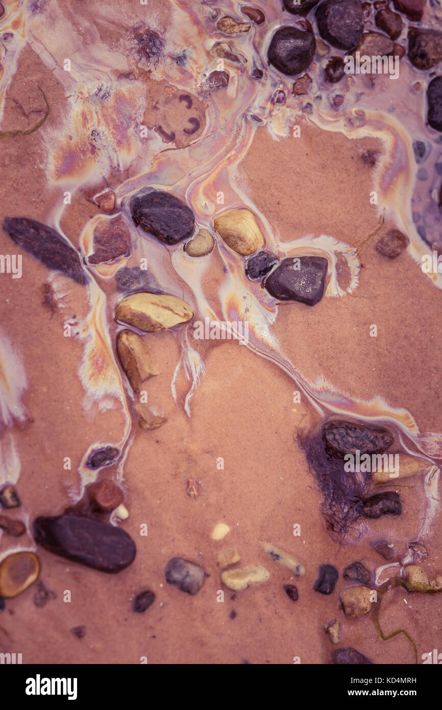 Pattern colorati di olio in spiaggia di sabbia. modelli di inquinamento sulla riva del Mar Baltico. colorato, forme astratte su una questione ecologica. Foto Stock