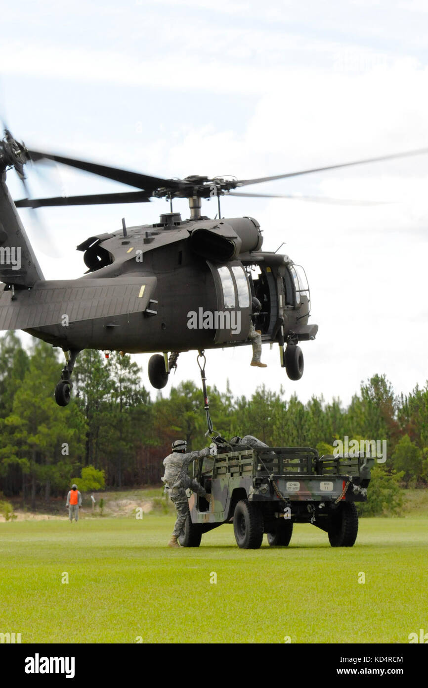 Esercito degli Stati Uniti, Sgt. Eddie Couthen e Private 1st Class Senquan alls, con il 351esimo Battaglione di supporto dell'aviazione, Guardia Nazionale dell'Esercito della S.C., agganciano un Humvee ad un falco nero UH-60 per esercitarsi nelle operazioni di carico di imbragatura nei cieli sopra Columbia, S.C., 13 luglio 2014. La formazione fa parte della preparazione pre-mobilizzazione dell'unità per il loro prossimo schieramento in Kuwait. (STATI UNITI Guardia Nazionale dell'esercito foto di Sgt. Brian Calhoun/rilasciato) Foto Stock