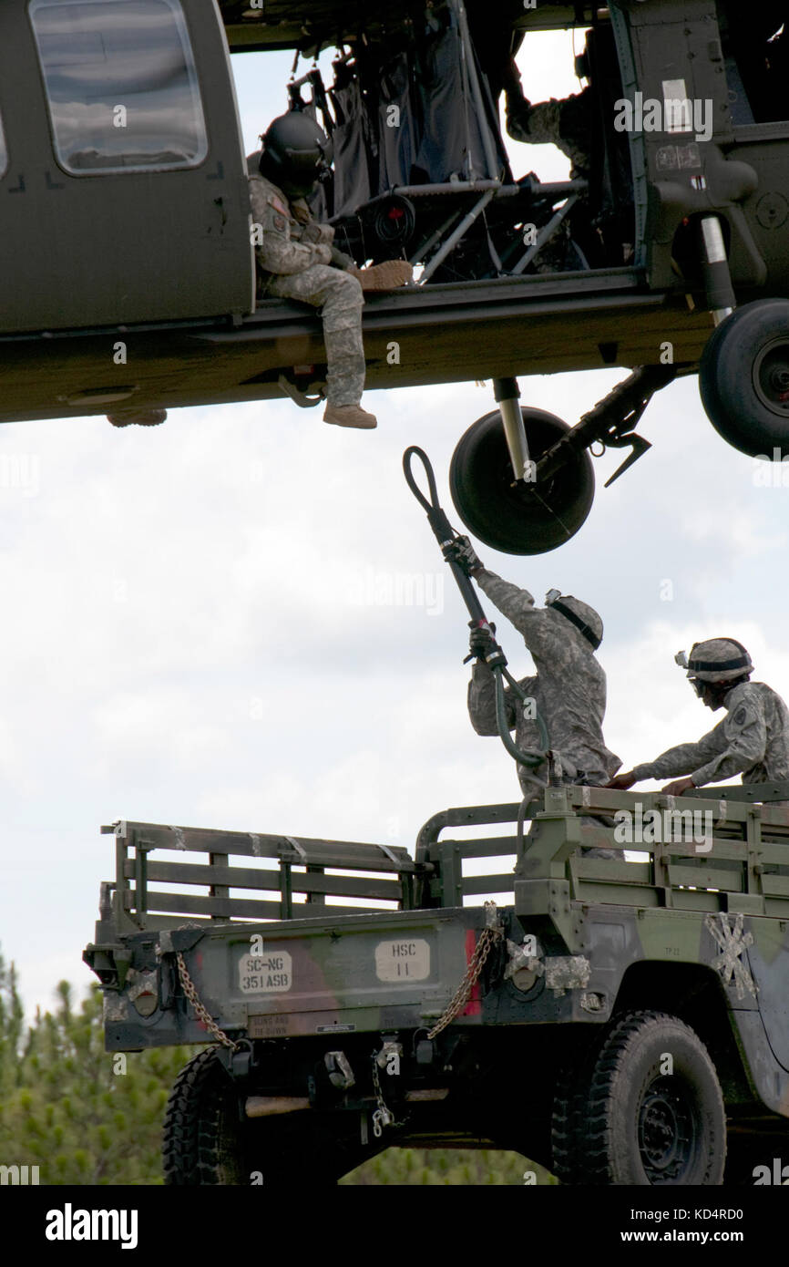 Esercito degli Stati Uniti, Sgt. Eddie Couthen e Private 1st Class Senquan alls, con il 351esimo Battaglione di supporto dell'aviazione, Guardia Nazionale dell'Esercito della S.C., agganciano un Humvee ad un falco nero UH-60 per esercitarsi nelle operazioni di carico di imbragatura nei cieli sopra Columbia, S.C., 13 luglio 2014. La formazione fa parte della preparazione pre-mobilizzazione dell'unità per il loro prossimo schieramento in Kuwait. (STATI UNITI Army National Guard foto di Capt. Jamie Delk/rilasciato) Foto Stock