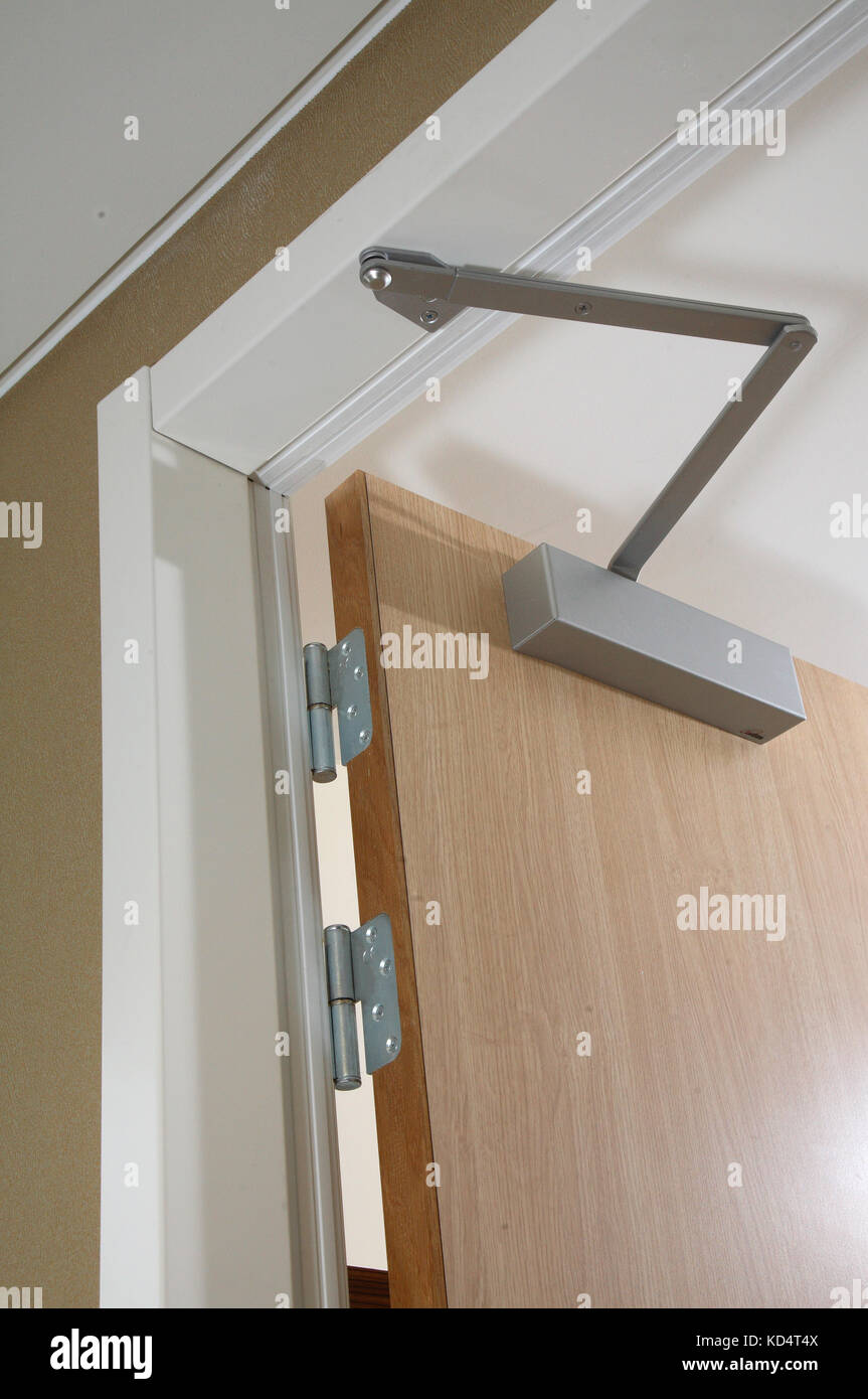 Primo piano di una moderna porta della camera d'hotel, aperta, con chiudiporta e altri accessori per soddisfare le più recenti normative antincendio Foto Stock