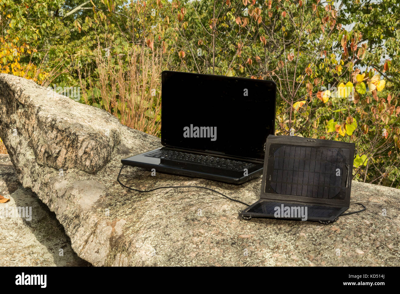 Pannello solare per ricaricare un computer portatile in un remoto la posizione di lavoro. Foto Stock