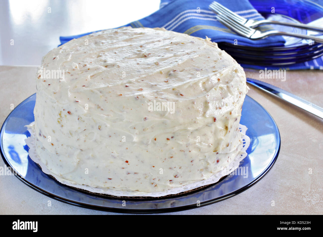 Una crema di formaggio e noci pecan torta smerigliato su un vetro blu. piastra di vetro naturale luce. torta è non decorato. Foto Stock