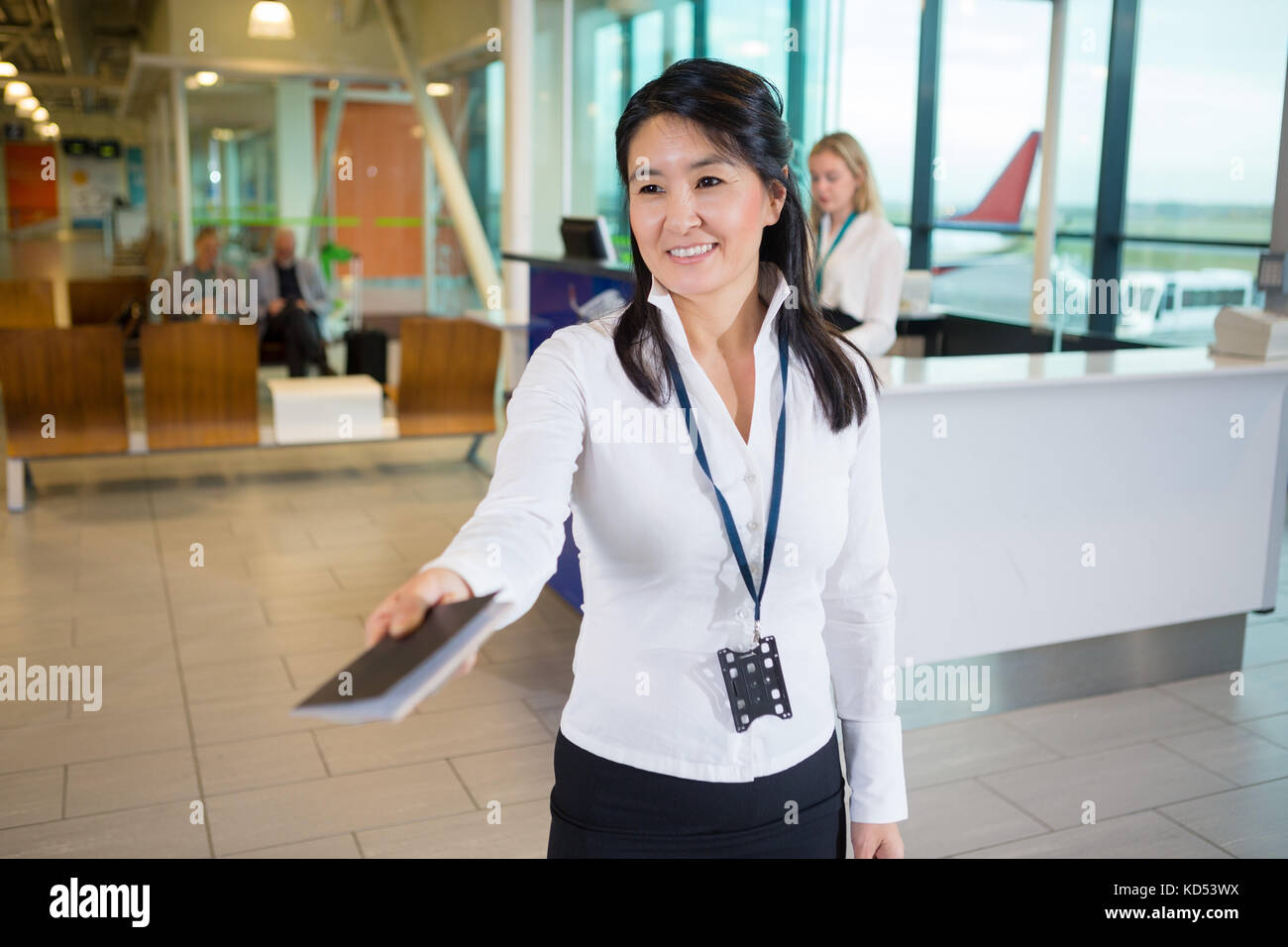 Sorridente metà femmina adulta membro dello staff dando il passaporto al terminal aeroportuale Foto Stock