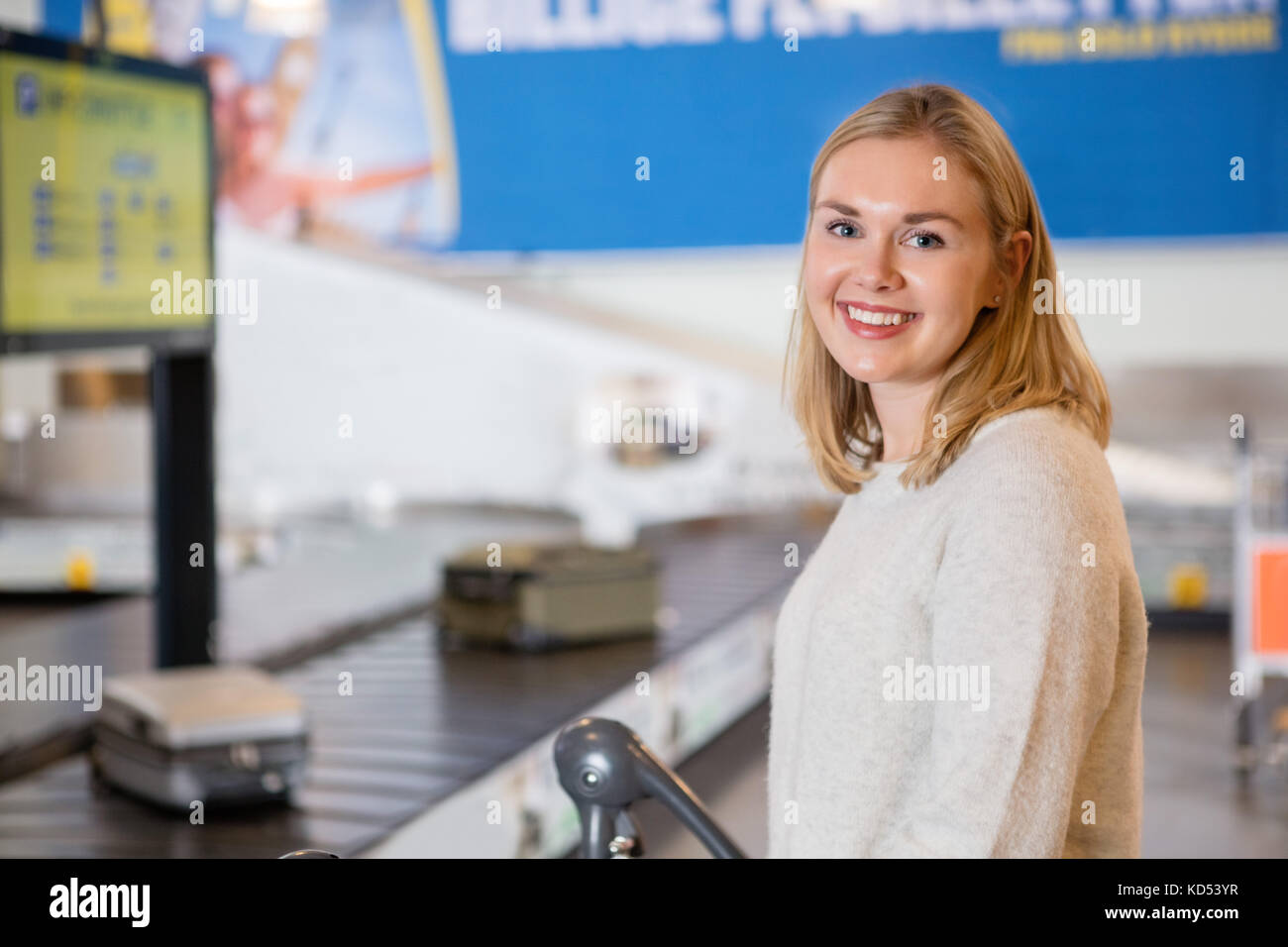 Ritratto di giovane e bella donna sorridente dal nastro trasportatore in aeroporto Foto Stock