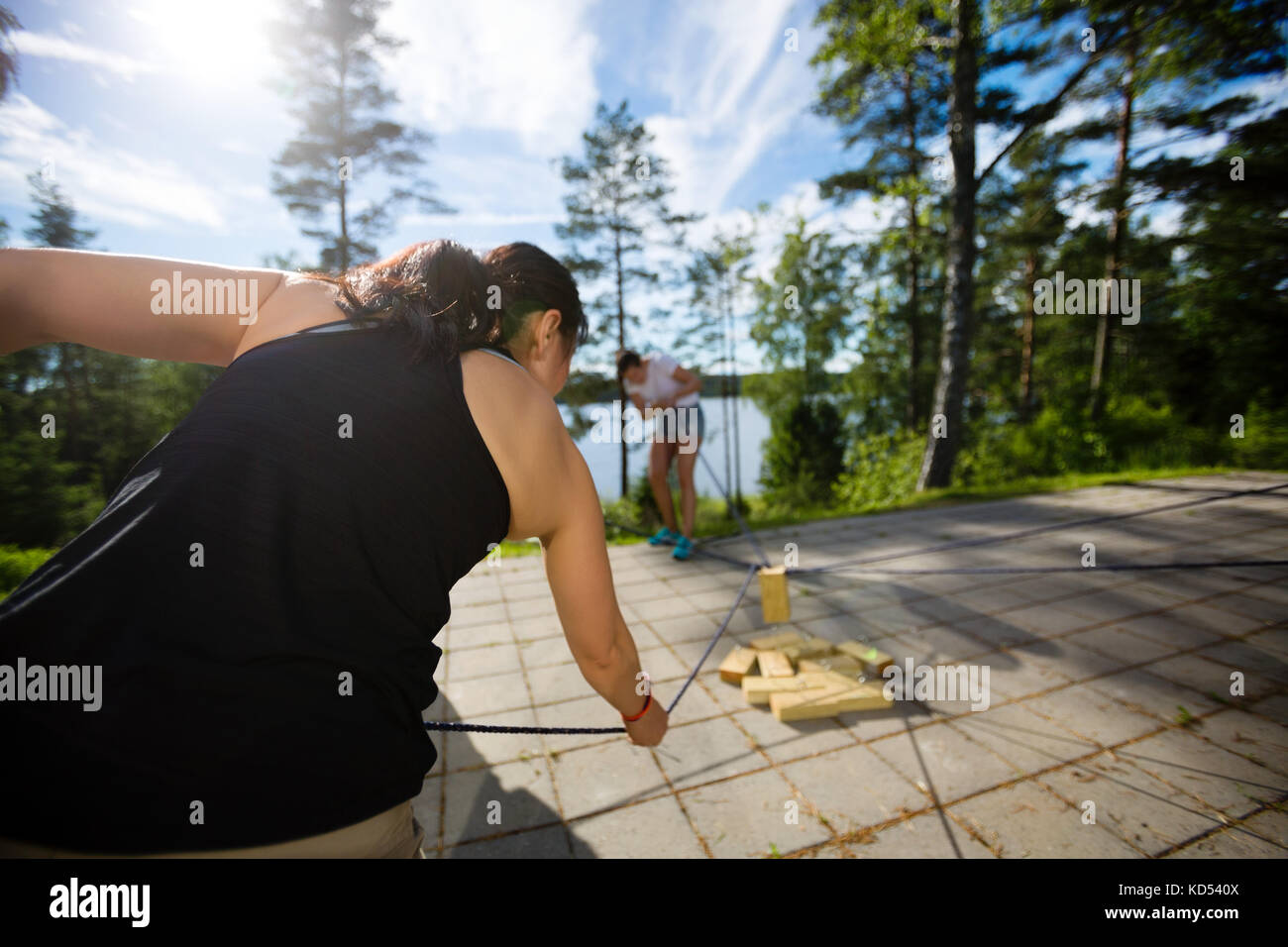 Vista posteriore della donna di prelevare il blocchetto in legno con fune sul patio in foresta Foto Stock