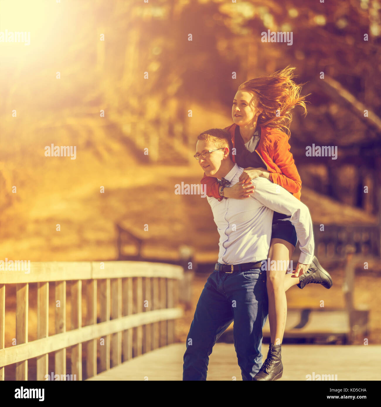 Felice l'uomo che porta la sua fidanzata sul retro sul ponte sopra il fiume. tono vintage Foto Stock