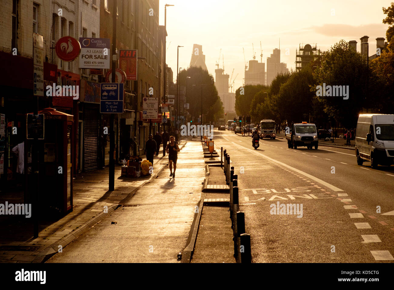 In tarda serata si può ammirare il sole verso le torri e la costruzione della City of London lungo la A11 Mile End Road Foto Stock
