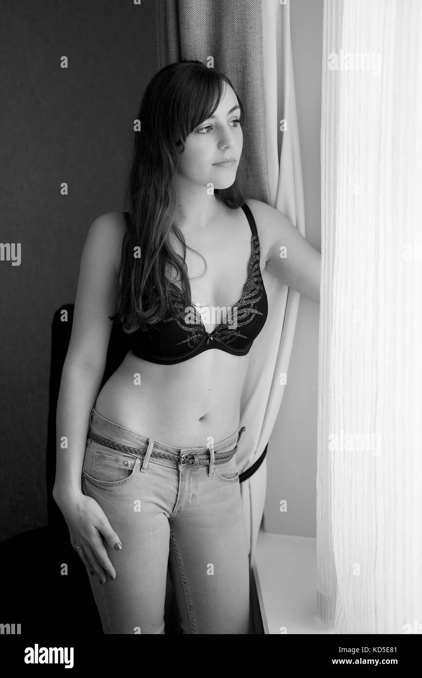 Bella bruna ragazza in jeans e un reggiseno nero top in una camera da letto posizione Foto Stock