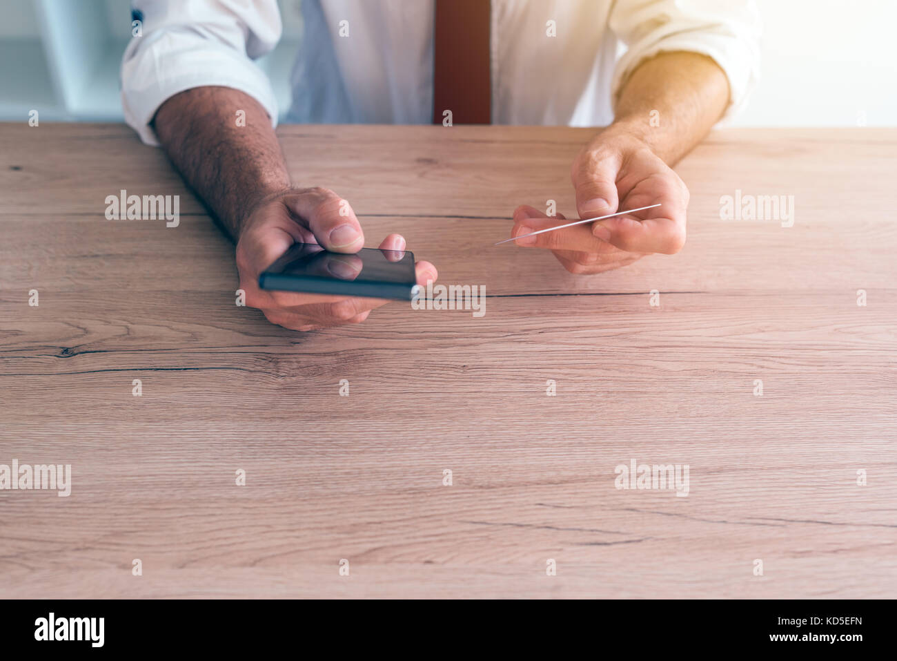 Mobile banking app smartphone utilizzato da parte dell'imprenditore a scrivania in ufficio. Adulto caucasico persona business il collegamento di carta di credito per internet online e-banking Foto Stock