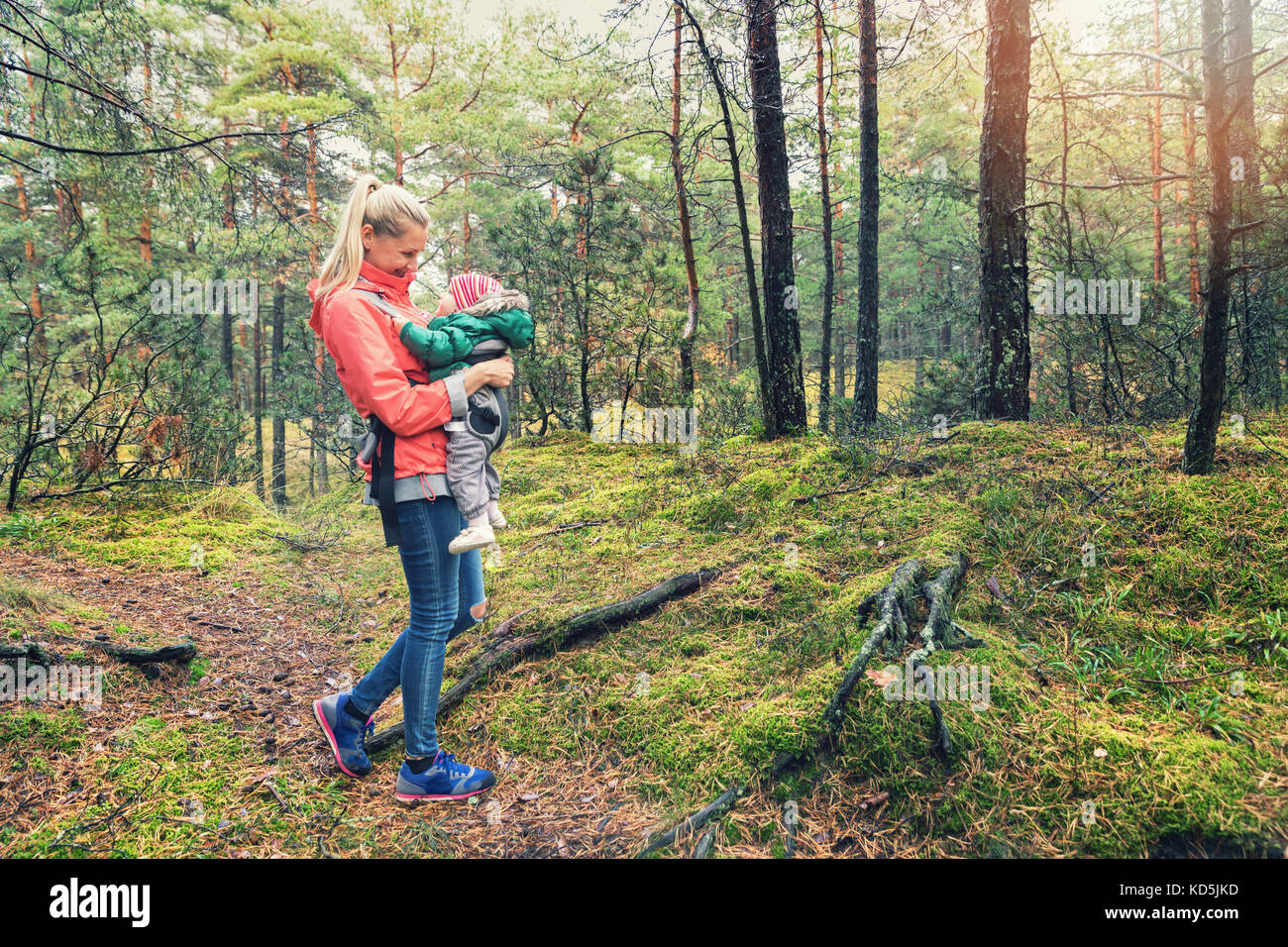 La madre a piedi nei boschi con il bambino nel sacchetto di canguro Foto Stock