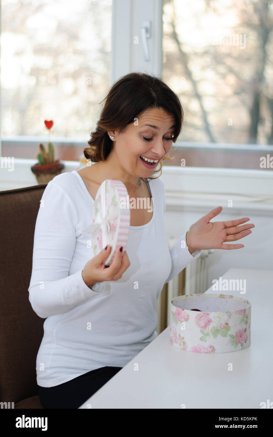 Donna di mezza età apre un presente ed è sorpreso Foto Stock
