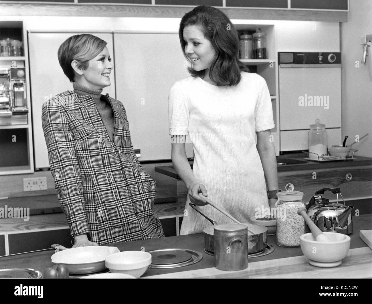 La foto Deve Essere Accreditata ©Alpha Press 050000 07/03/1967 Due compagni insoliti in cucina, Diana Rigg, della serie televisiva 'The Avengers', e del famoso modello adolescente Twiggy al 1967 Ideal Home Exhibition di Olympia, Londra. The All Electric Kitchen è una replica esatta della casa di Miss Rigg. Foto Stock