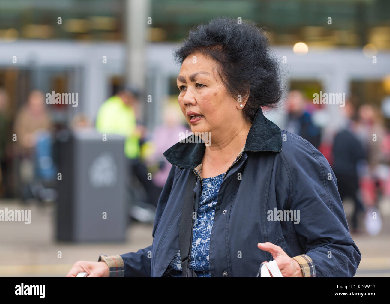 Persone di mezza età donna asiatica a camminare in una città frenetica in Inghilterra, Regno Unito. Foto Stock