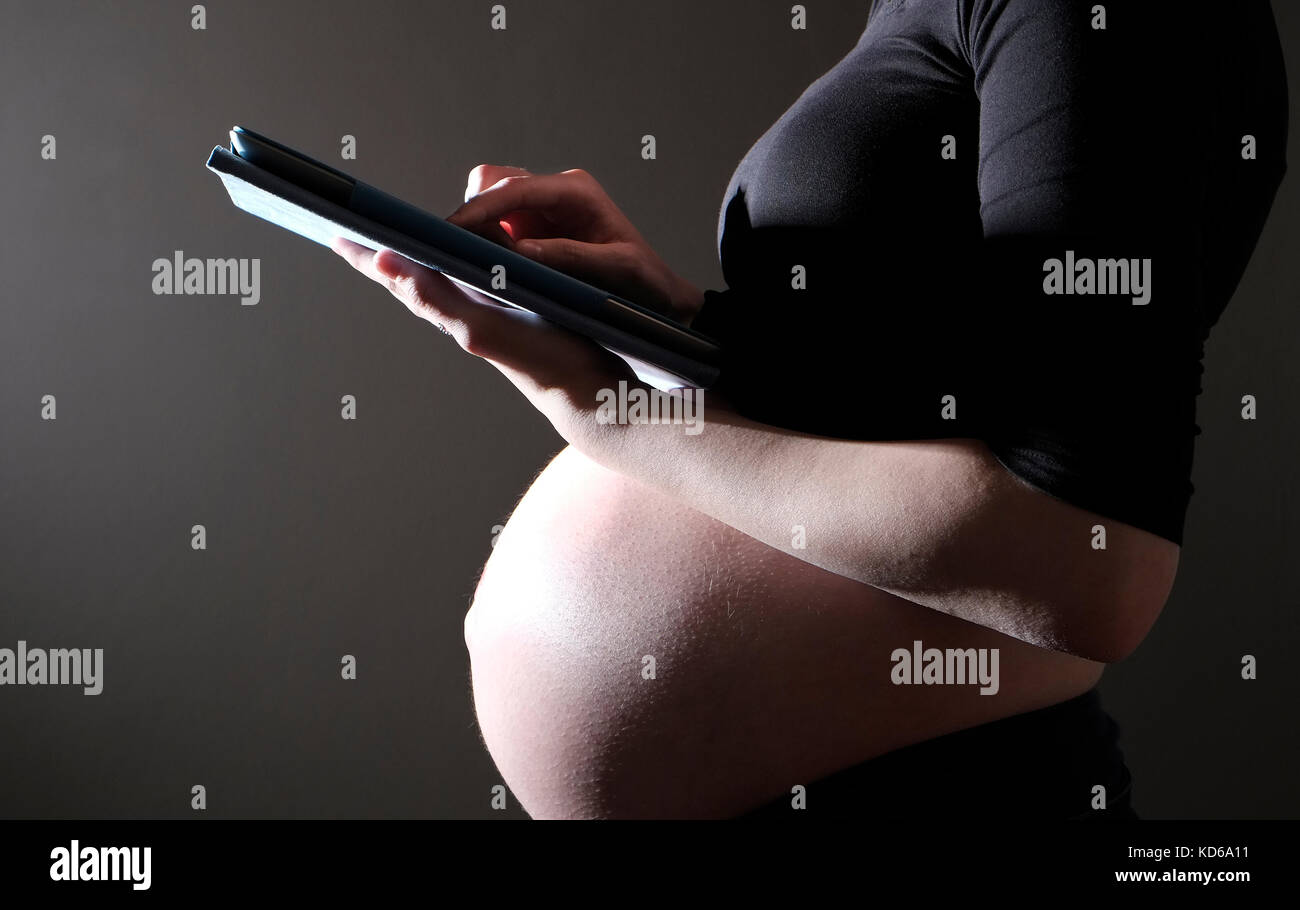 Gravidanza adolescente utilizzando computer tablet ipad Foto Stock
