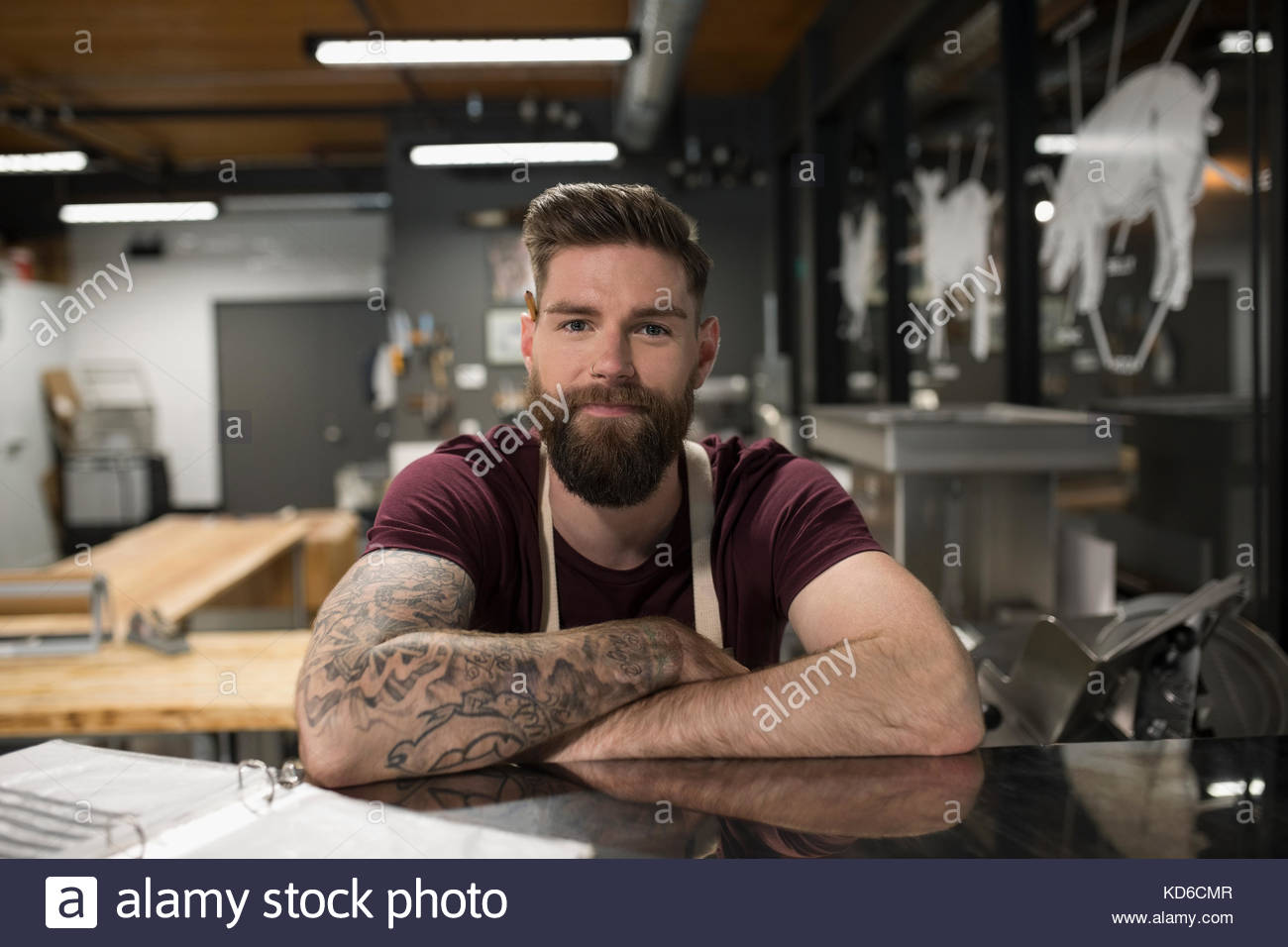 Ritratto sicuro macellaio maschio con tatuaggi e barba in macelleria Foto Stock