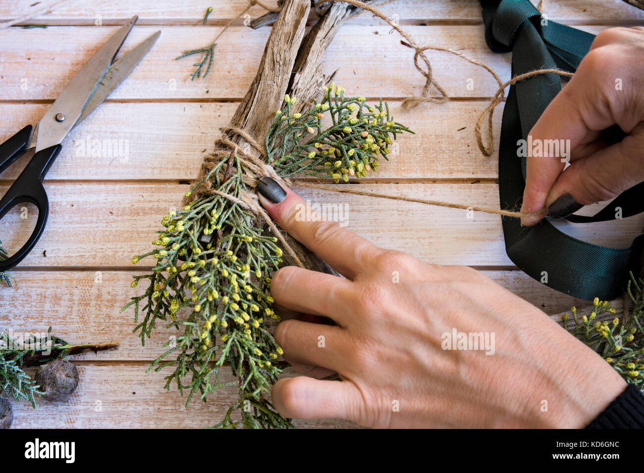 Fioraio al lavoro: creazione di una ghirlanda di legno con red barries, circondato dalle arti e mestieri. Foto Stock