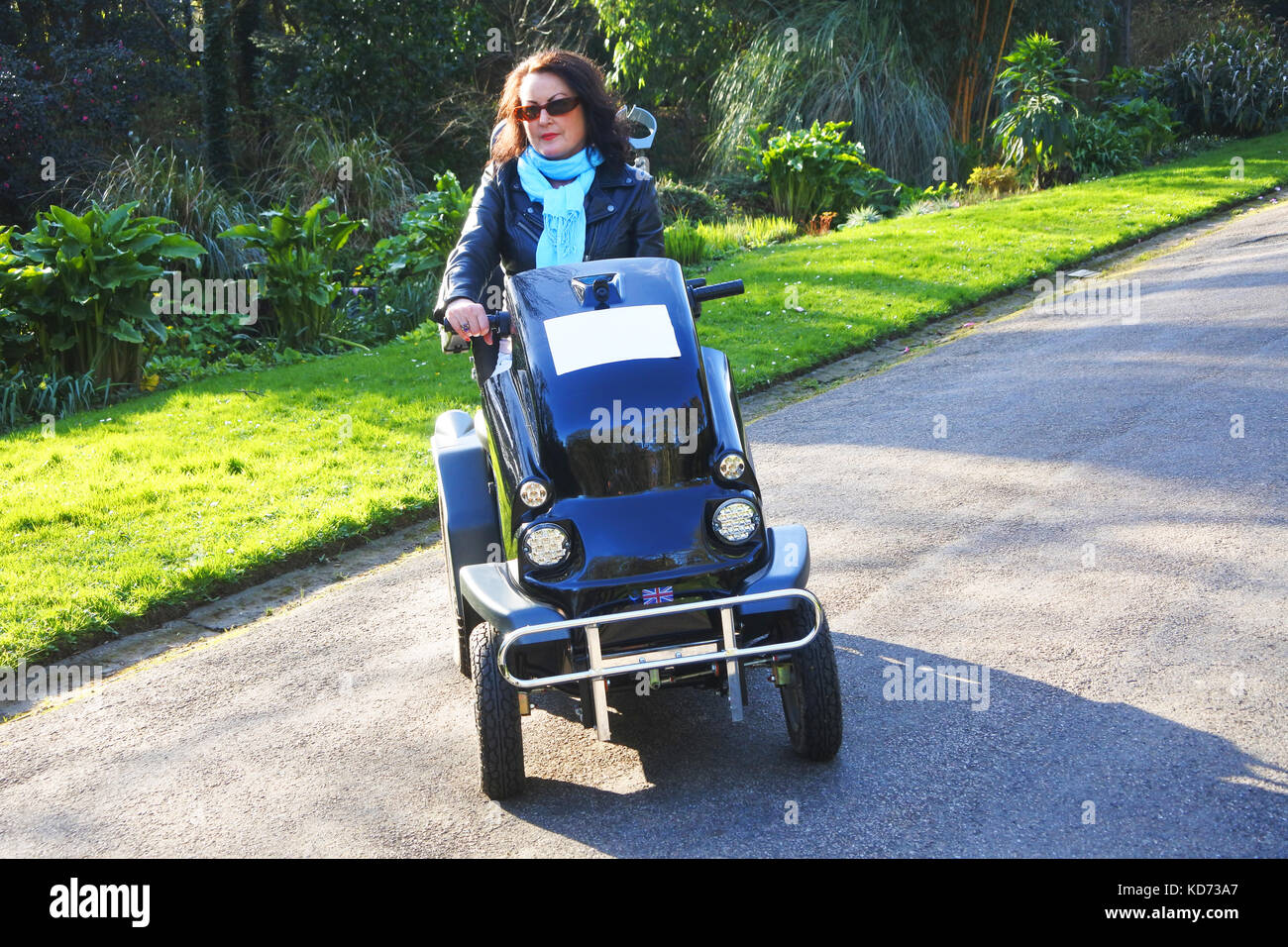 Donna attraente usando una sedia a rotelle motorizzata - John Gollop Foto Stock