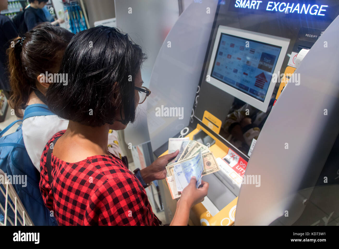 Le donne lo scambio di denaro in una macchina smart. prelievo contanti da un bancomat in un negozio i turisti di cambiare i soldi in un bancomat, Giappone. Foto Stock