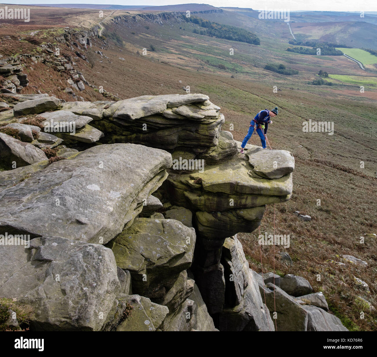 Un scalatore le chiamate verso il basso per il suo compagno di arrampicata da una sporgenza sul bordo Stanage vicino a Hathersage nel Derbyshire Peak District UK Foto Stock