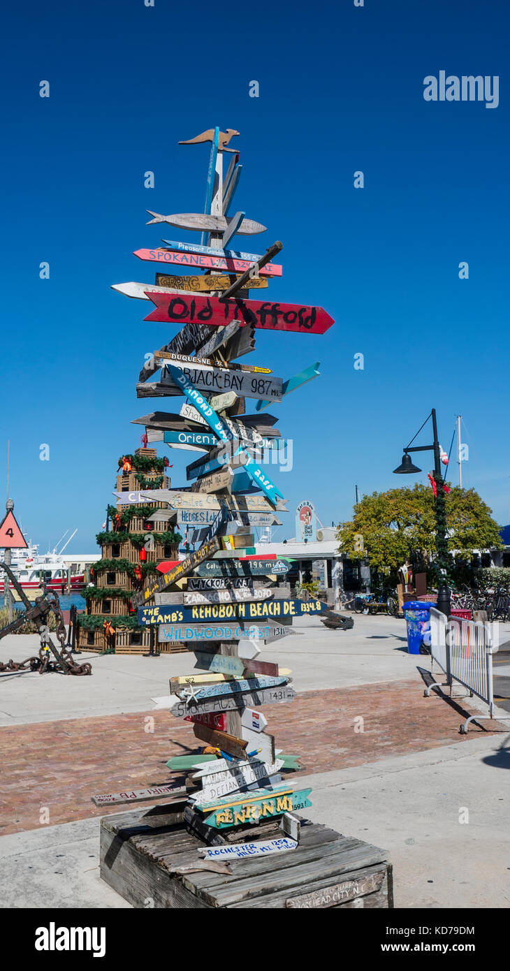 Segnaletica direzionale da key west a destinazioni con frecce e chilometraggio con natale lobster pot di albero in background. Foto Stock