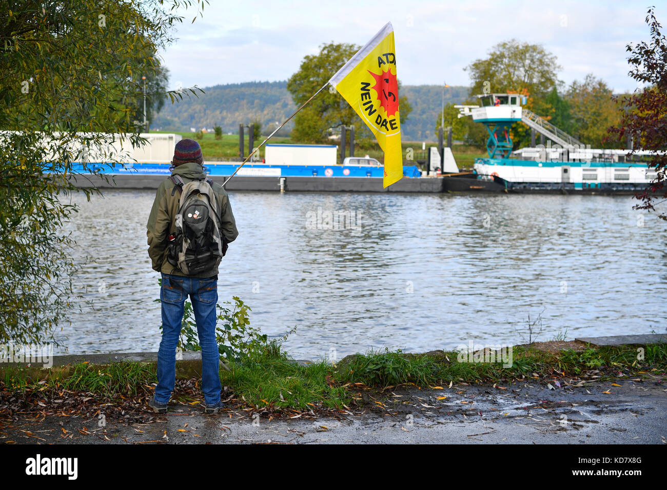 Gundelsheim, Germania. 11 ottobre 2017. Un manifestante osserva le navi passare sul fiume Neckar a Gundelsheim, in Germania, 11 ottobre 2017. È il terzo dei cinque trasporti di ruote della società energetica EnBW, che spedisce scorie nucleari da Obrigheim a un deposito temporaneo a Neckarwestheim. Credito: Uwe Anspach/dpa/Alamy Live News Foto Stock