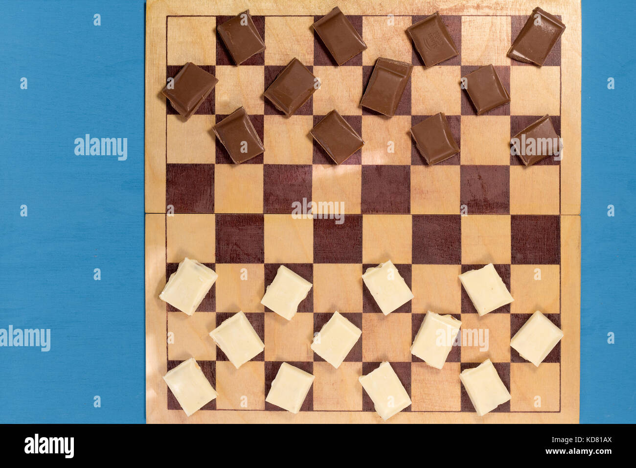 Barre di cioccolato marrone e bianco su una scacchiera. Gioco, rivalità, concorrenza Foto Stock