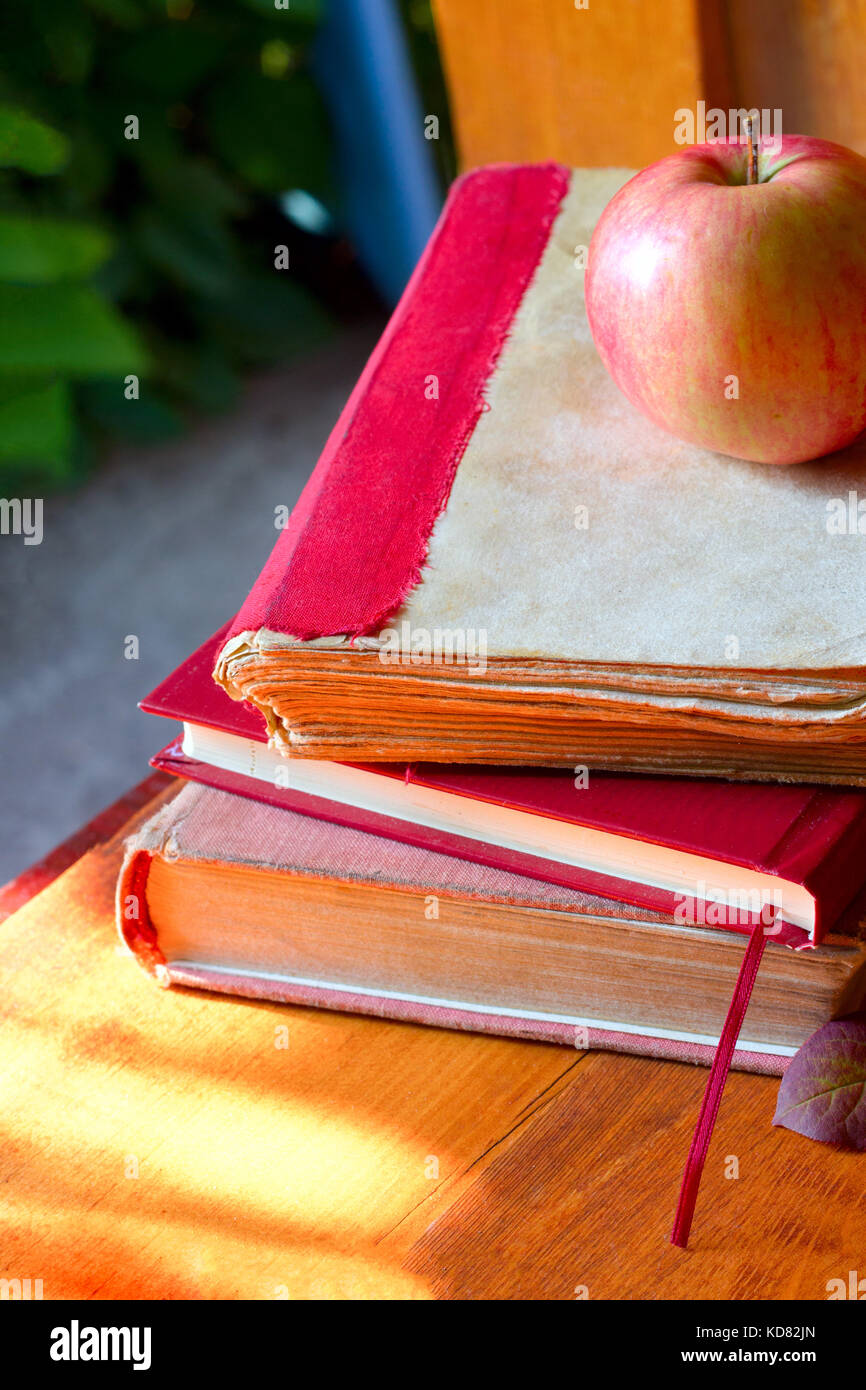 Si torna a scuola concetto. Lavagna con libri e apple sullo sfondo di legno. Foto Stock