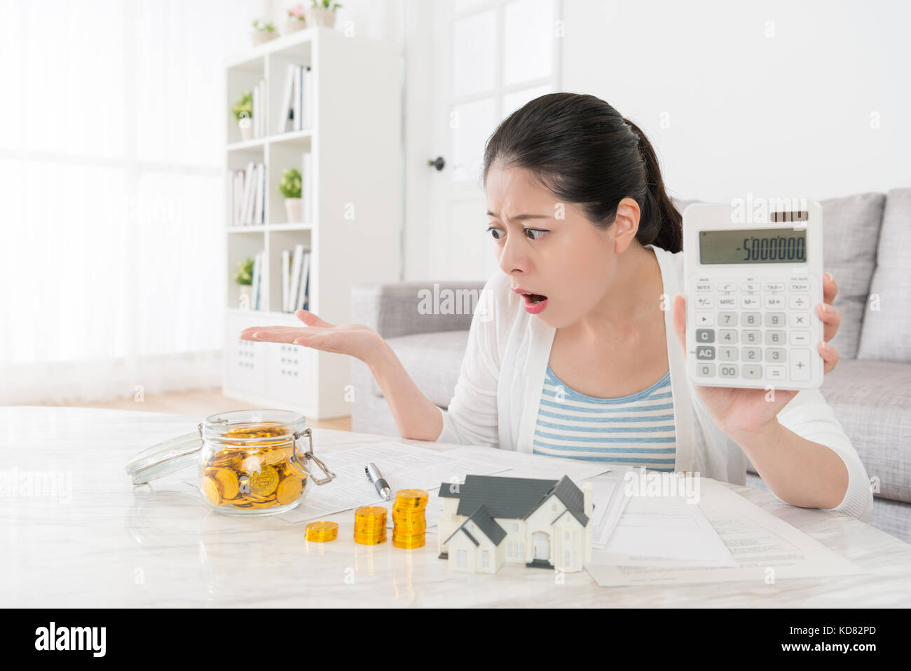 Infelice giovane madre utilizzando la calcolatrice mostra il numero negativo quando lei nuovo piano casa e famiglia di conteggio salvataggio di constatazione non basta sentirsi sconvolto. Foto Stock