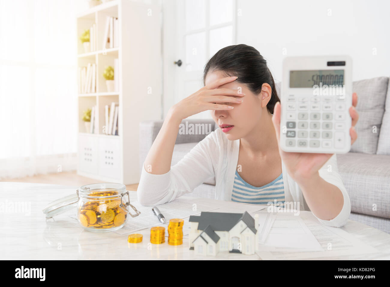 Attraente bella donna utilizzando la calcolatrice di conteggio deposito personale sensazione infelice perché il suo risparmio di denaro presentando un numero negativo lo stato. selet Foto Stock