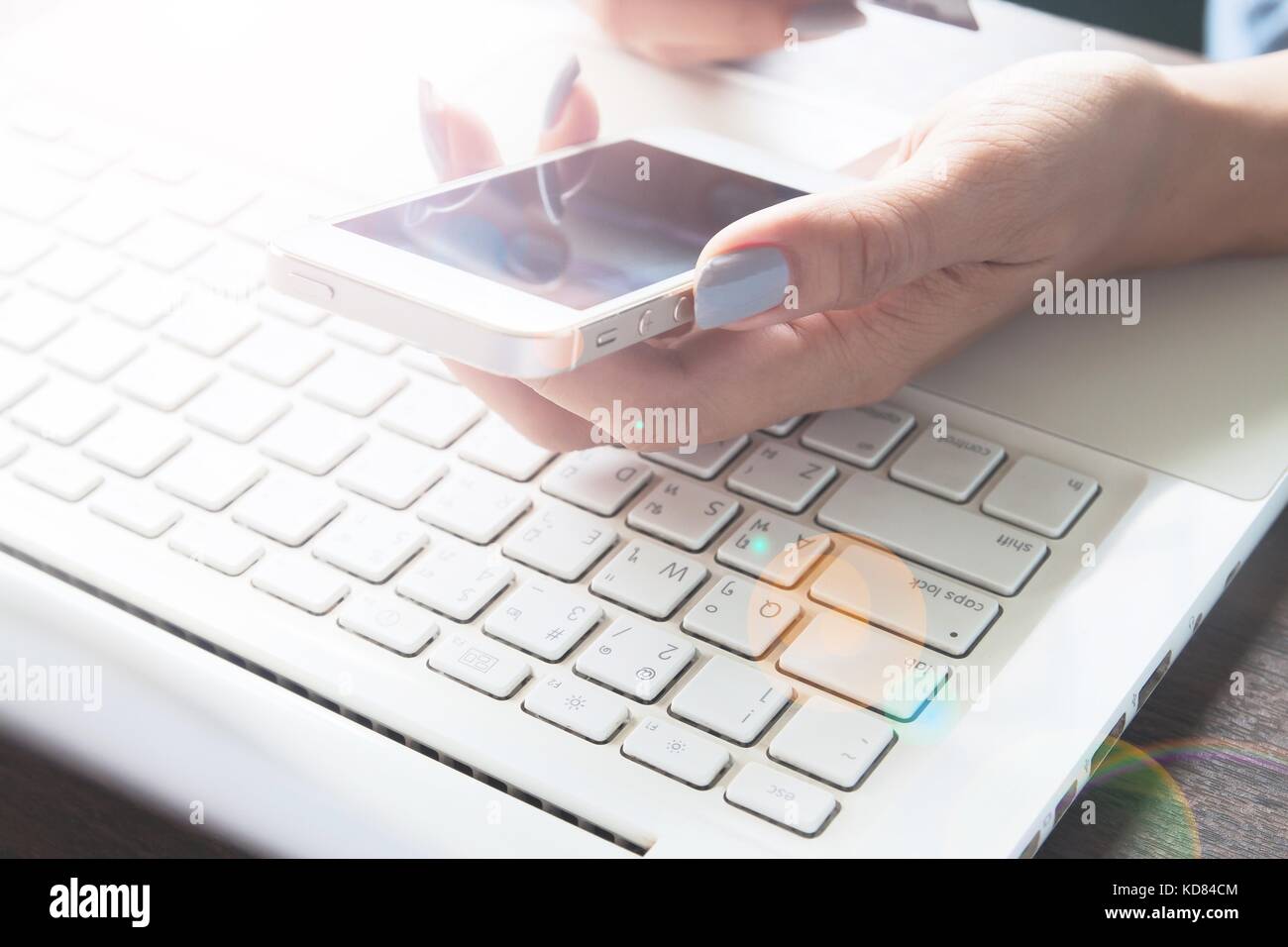 Donna mano utilizzando il dispositivo mobile e il computer portatile sulla sua scrivania, lo shopping online e il concetto di marketing Foto Stock