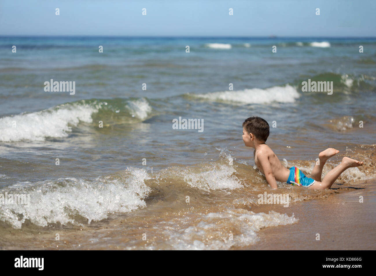 Ragazzo che si trova nel surf sulla spiaggia, Corfù, Grecia Foto Stock
