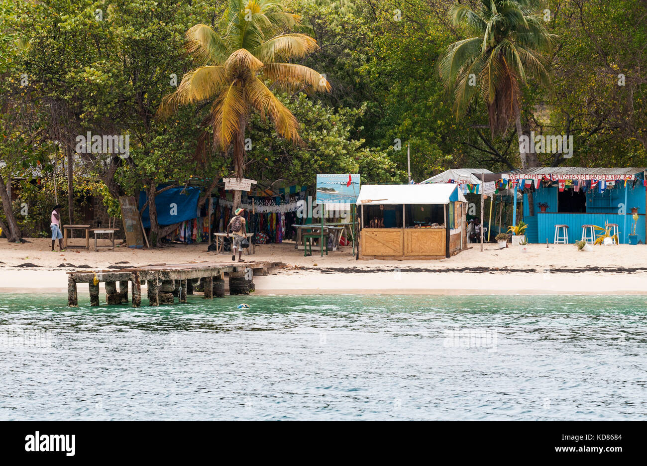 Pittoresca spiaggia di scena a salt whistle bay, mayreau, con jetty, sarong, bar e negozio di souvenir shack che vende viaggi in barca #2: Saint Vincent e Grenadine &. Foto Stock