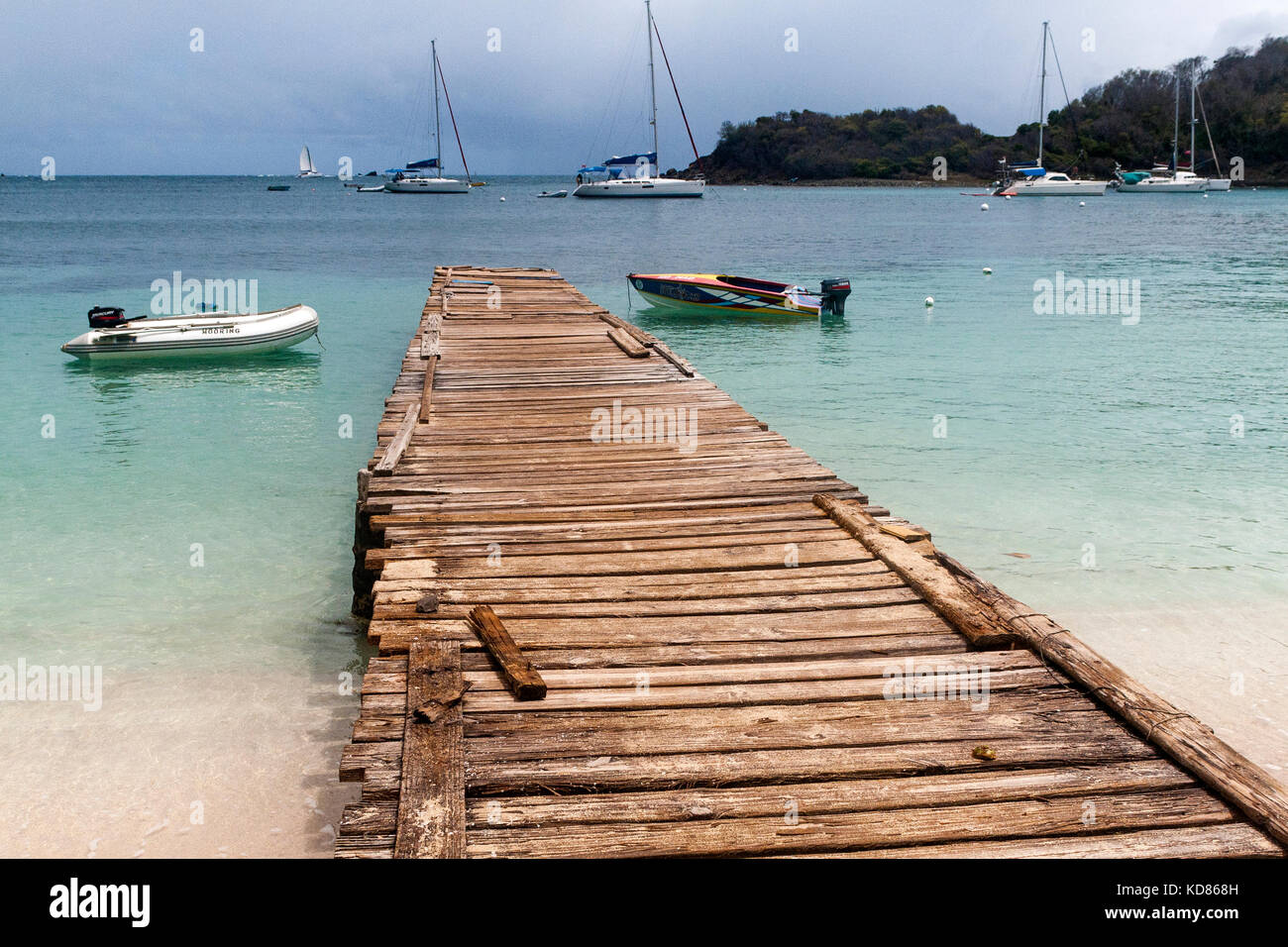 Vista del molo - che guarda al mare lungo il molo traballanti da salt whistle bay, mayreau. ormeggiate barche, penisola, e Caraibi vista oceano: Saint Vince Foto Stock