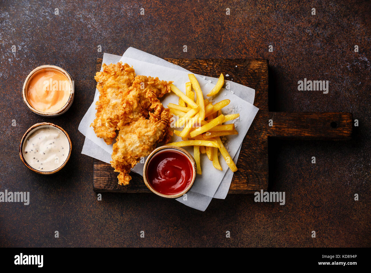 Pesce e Patatine british fast food con tre salsa popolare per la scelta su sfondo marrone Foto Stock