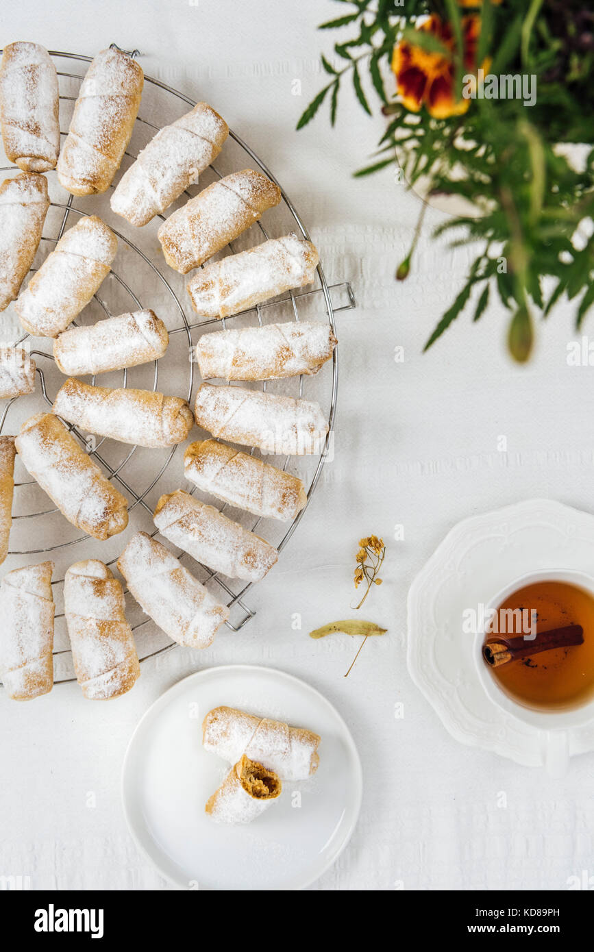 Bagno turco biscotti farciti con mela e cannella su una griglia di raffreddamento su uno sfondo bianco fotografata da vista dall'alto. Una tazza di tè, una piccola targa con c Foto Stock