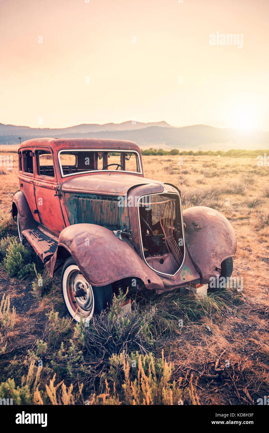 Vecchio arrugginito antique auto abbandonate in un campo al tramonto Foto Stock