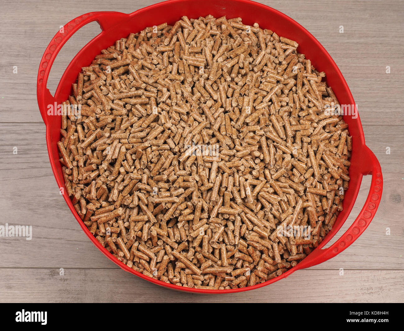 L'energia alternativa concetto, pellet di legno in un cesto di rosso su un pavimento di legno Foto Stock