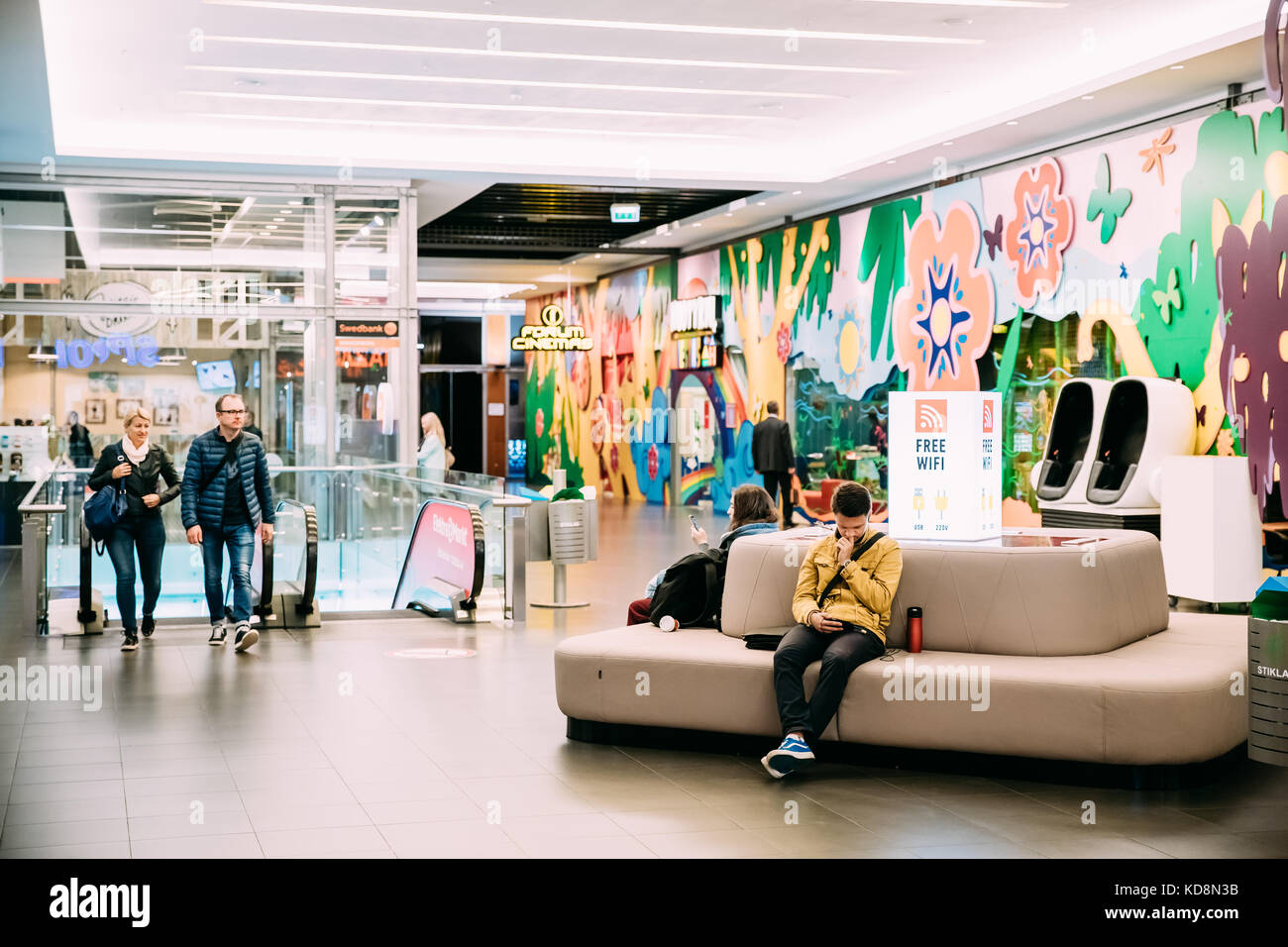 Vilnius, Lituania - 21 settembre 2017: la gente seduta al posto del wifi gratuito e ricarica per telefono nel moderno centro commerciale akropolis Foto Stock