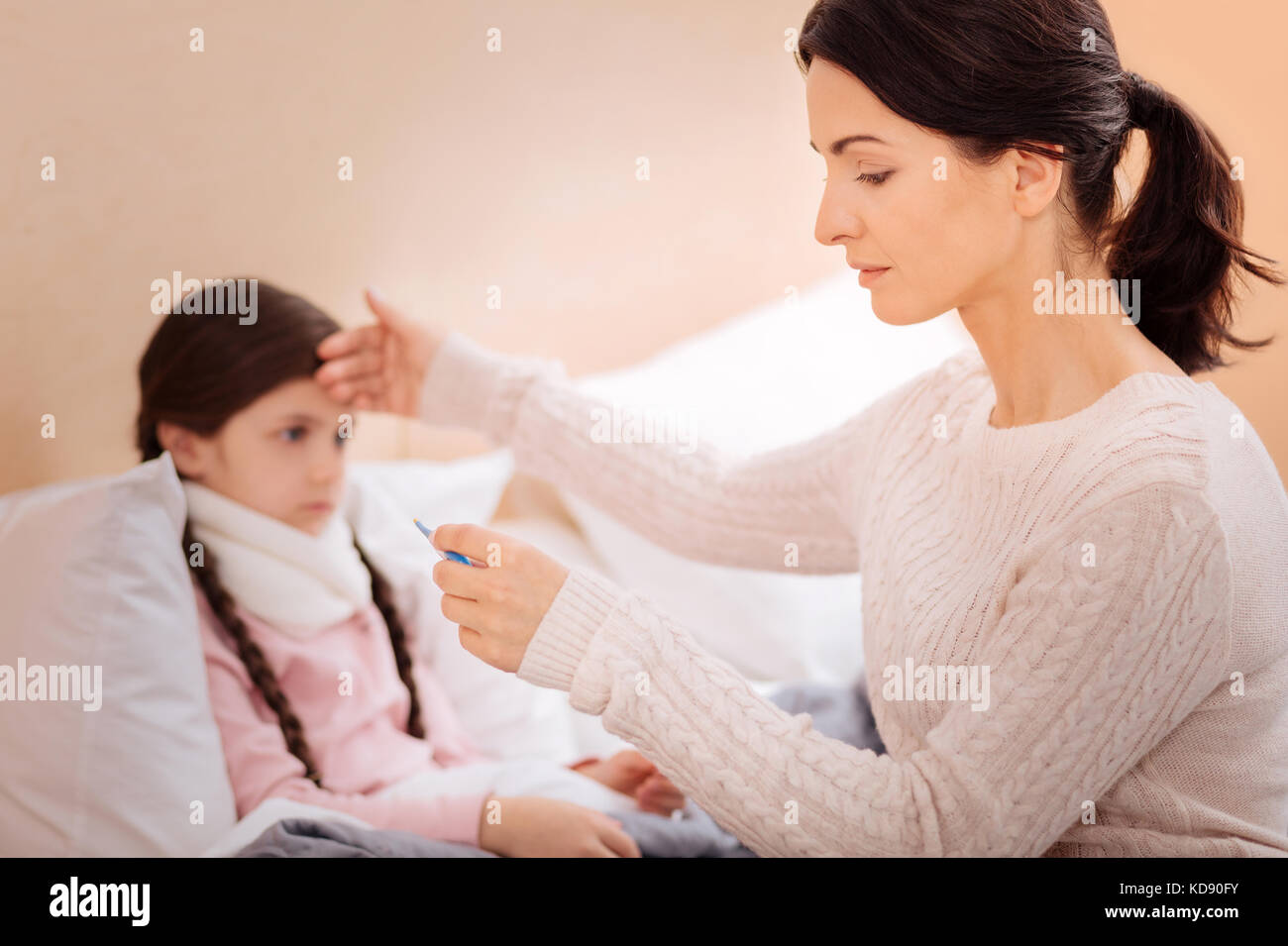 Madre premurosa che misura la temperatura del suo bambino Foto Stock