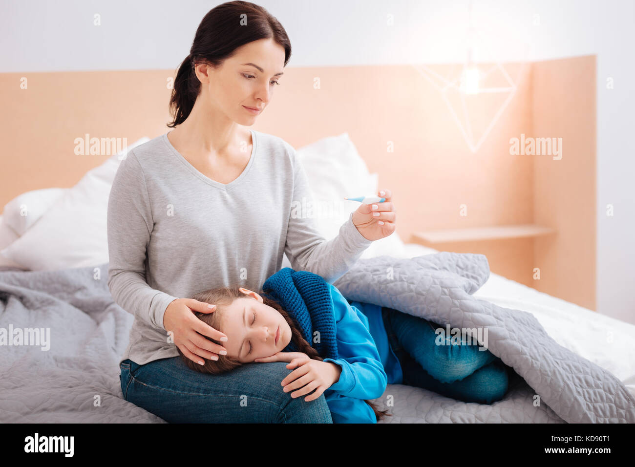 Madre concentrata seduta con il suo bambino malato Foto Stock
