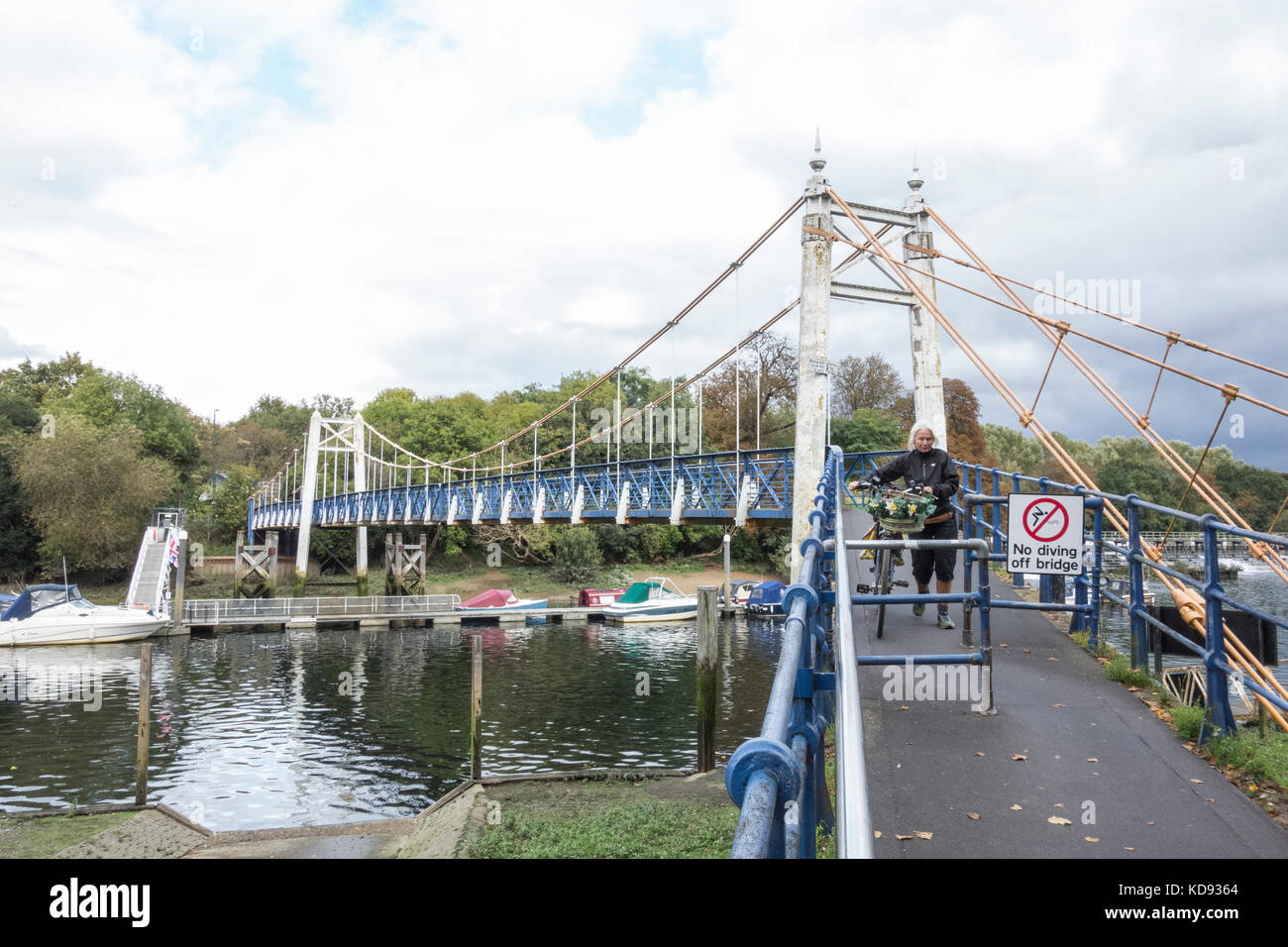 Un ciclista smonta e cammina sul ponte pedonale di Teddington Lock sul Tamigi, Teddington, Inghilterra, Regno Unito Foto Stock