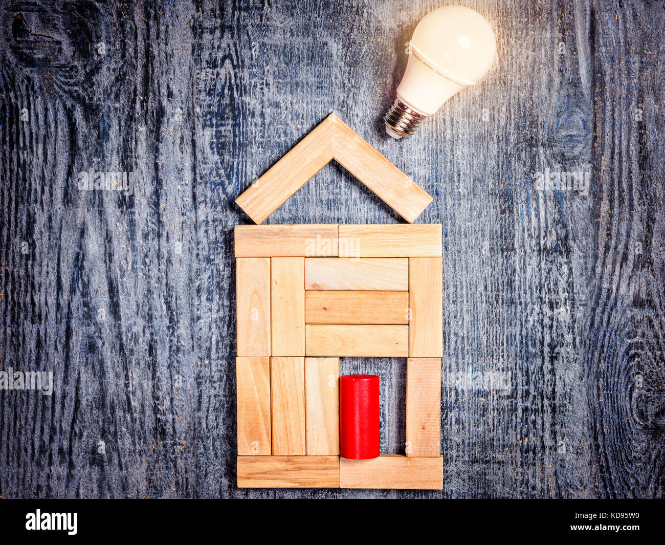 Forma di casa sopra albero in legno scuro e sfondo lampadina led. imitazione di riscaldamento di rame o caldaia e condizionatore aria Foto Stock