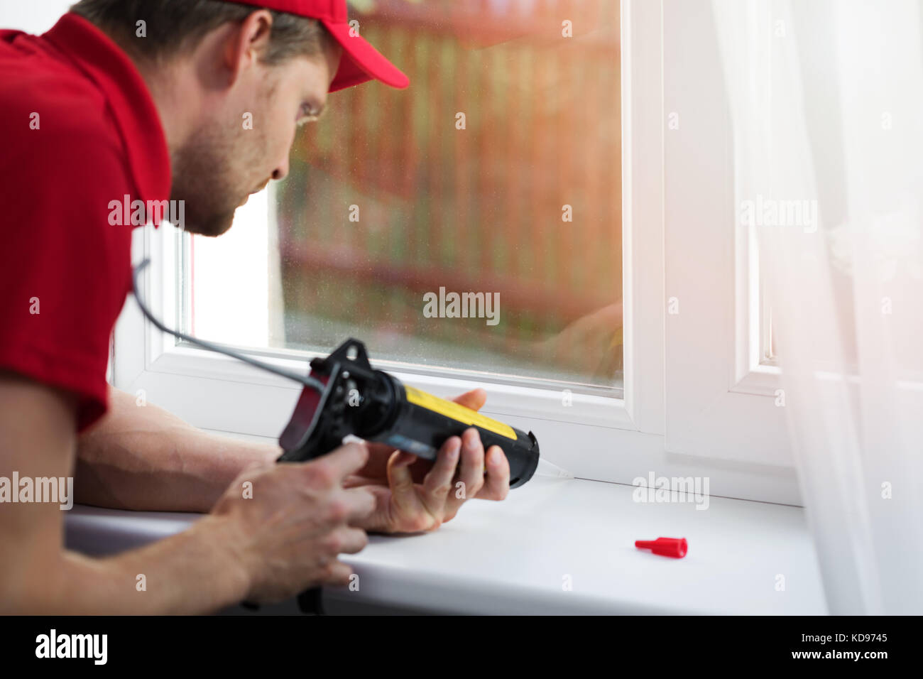 Lavoratore di applicare sigillante al silicone sotto il telaio del finestrino Foto Stock